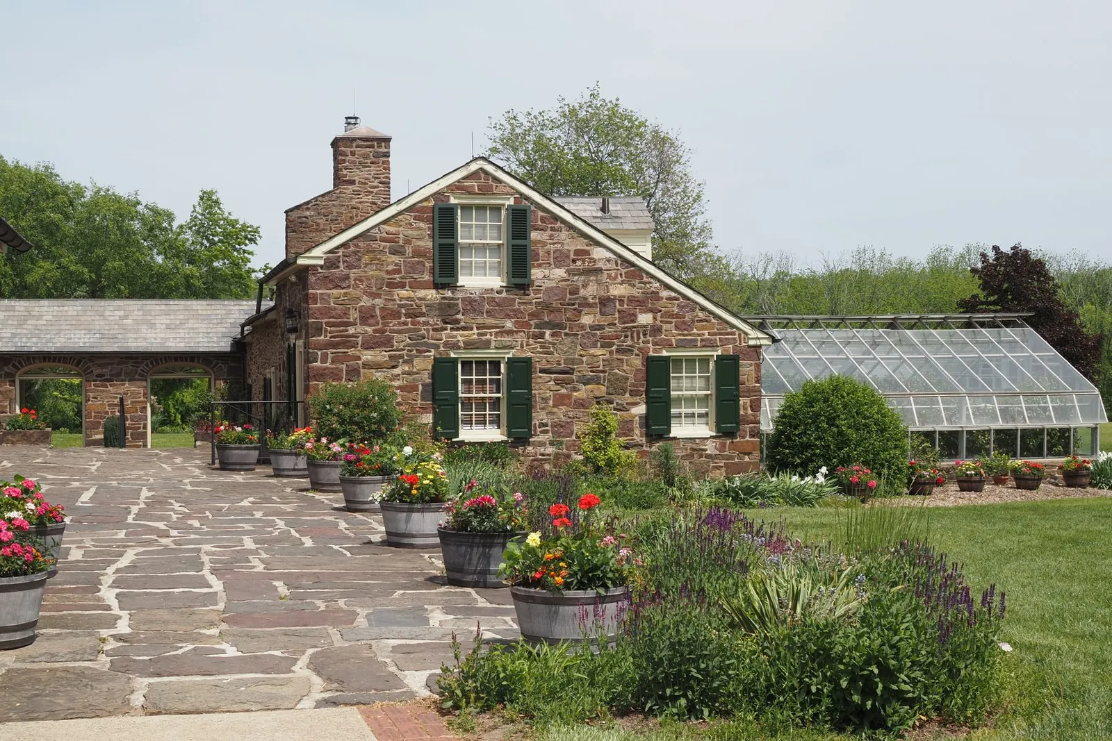 Fieldstone farmhouse with a stone chimney, flagstone patio and an attached greenhouse