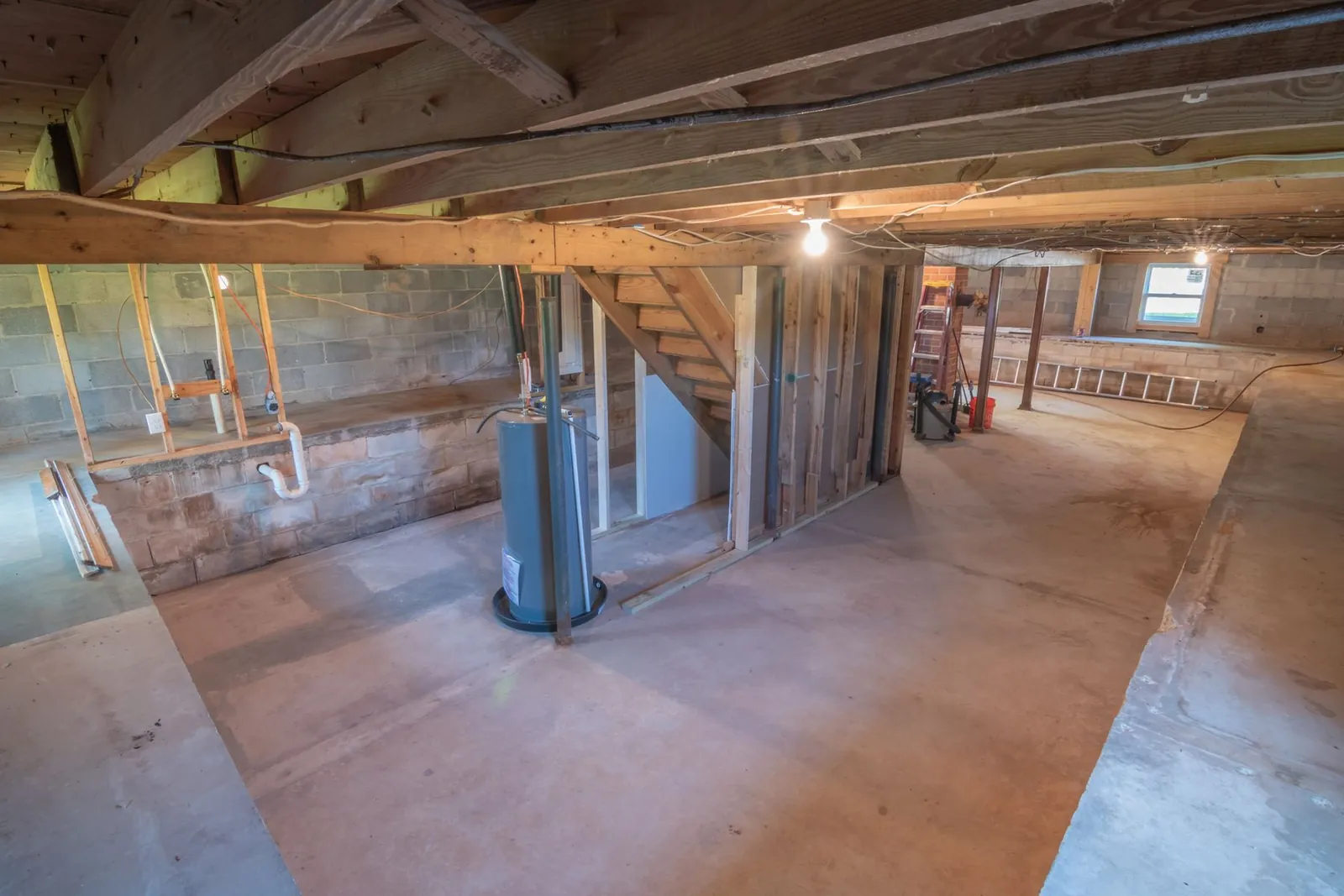 Unfinished basement with a gas water heater, vent pipe and block foundation walls