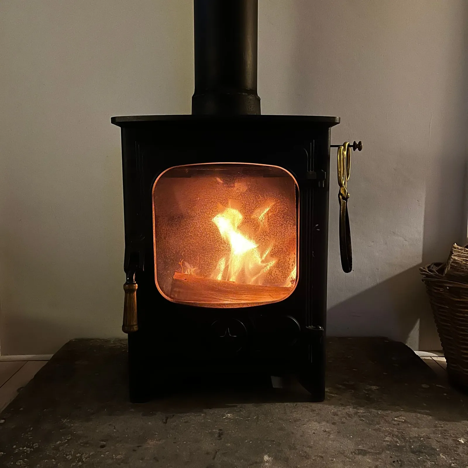 Black cast-iron wood stove with a glowing fire behind its glass door